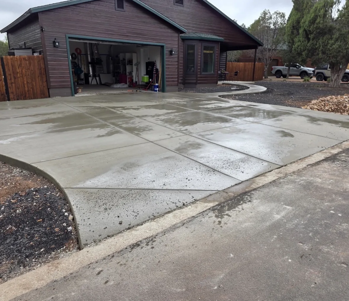 New concrete driveway with saw-cut control joints and a curved edge, poured up to the street