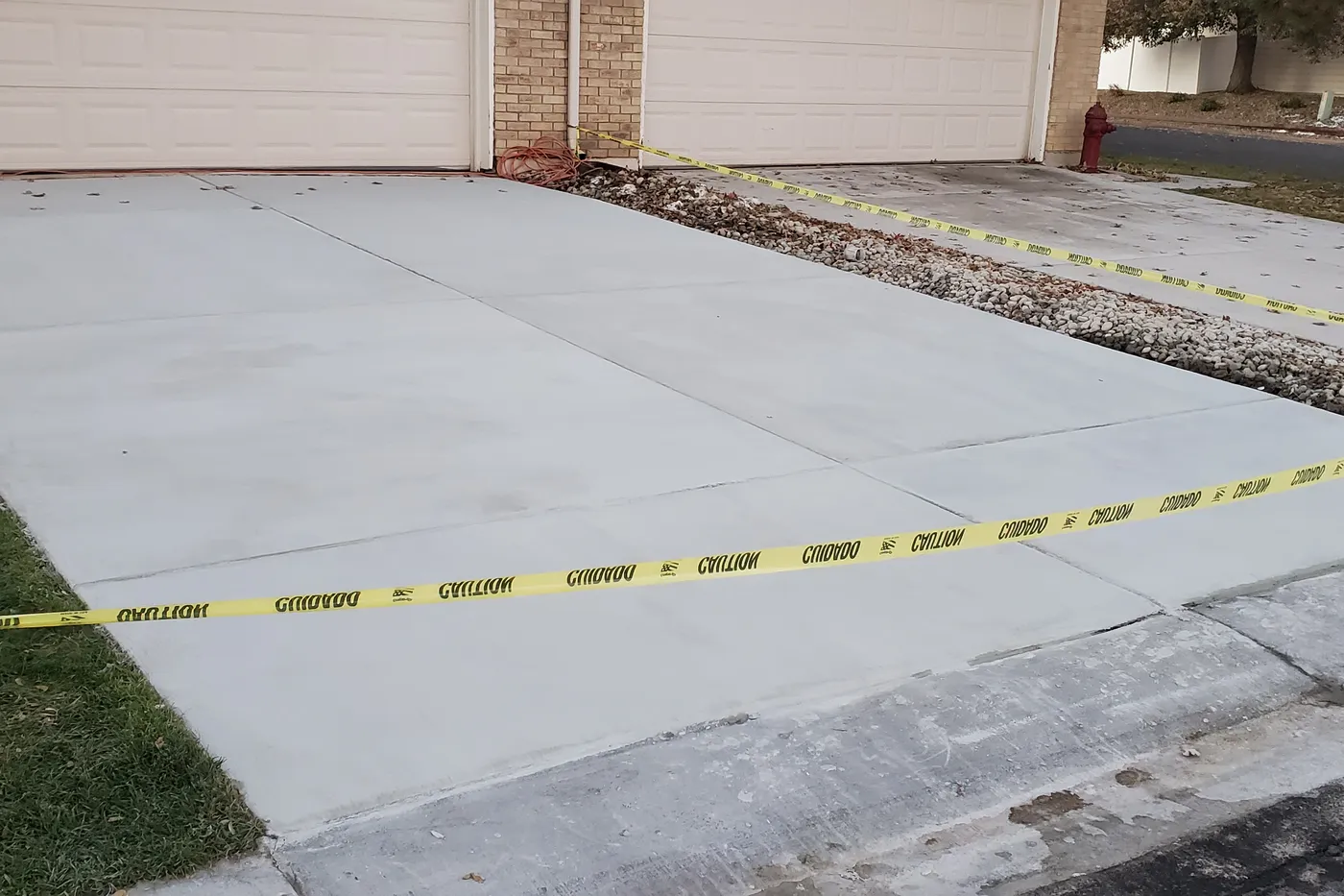 Freshly resurfaced concrete driveway taped off while the overlay cures